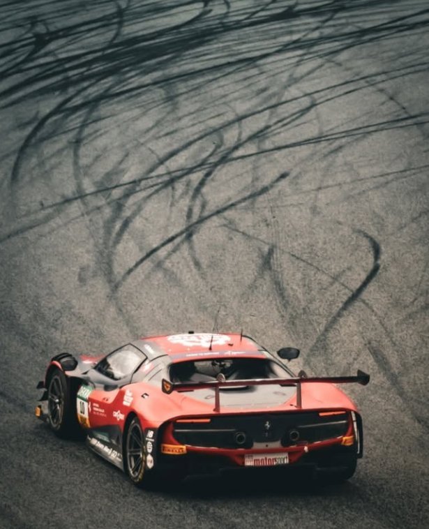 Roter Ferrari GT3-Rennwagen auf nasser Strecke mit Reifenspuren im Asphalt – Event-Fotografie WOLF[F]OTO